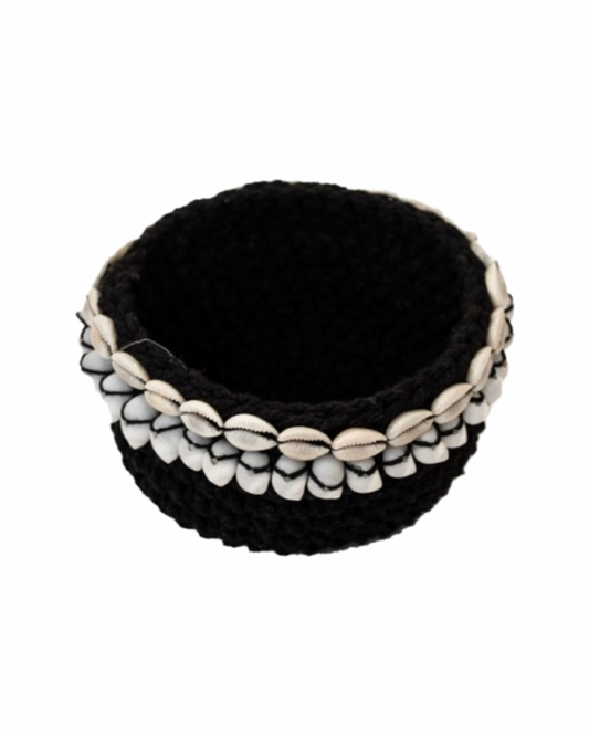 A small black crochet basket with white shells wrapped around the basket. 